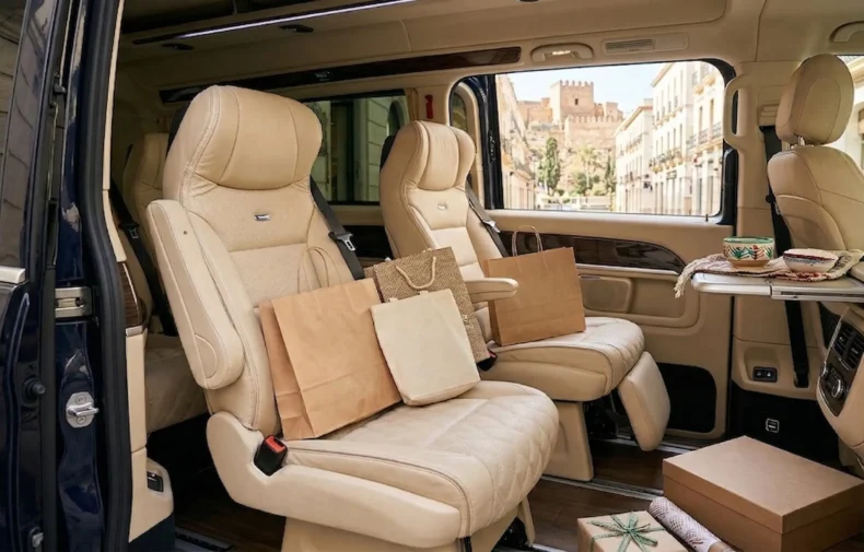 Detalle del interior espacioso de un vehículo de traslado privado con bolsas de compras exclusivas en el asiento.